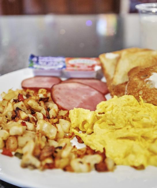 Breakfast plate with scrambled eggs, ham, roasted potatoes, and toast