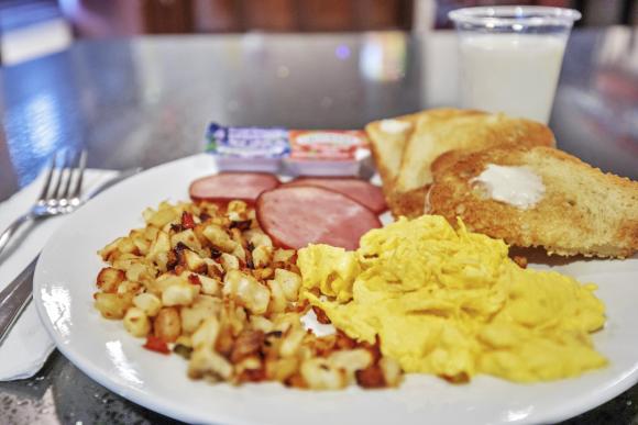 Breakfast plate with scrambled eggs, ham, roasted potatoes, and toast