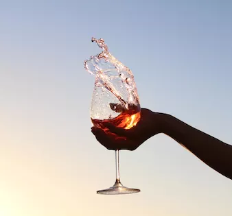Close up of a hand with a goblet of splashing red wine