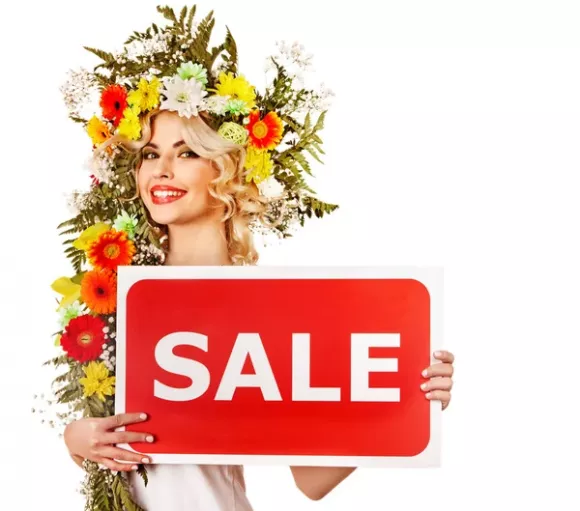 Lady with flower headdress holding "sale" sign